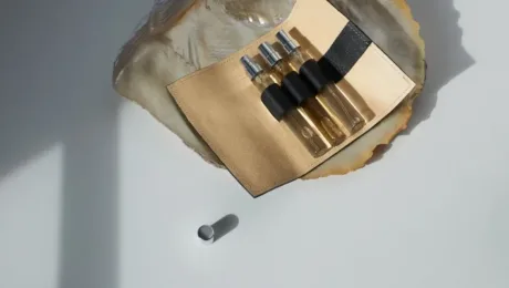 Yak zberihaty parfumeriyu ta dekantovani vidlyvy Open tan leather roll containing four glass dropper bottles with clear liquid, placed on a pale surface; a small cap lies nearby.