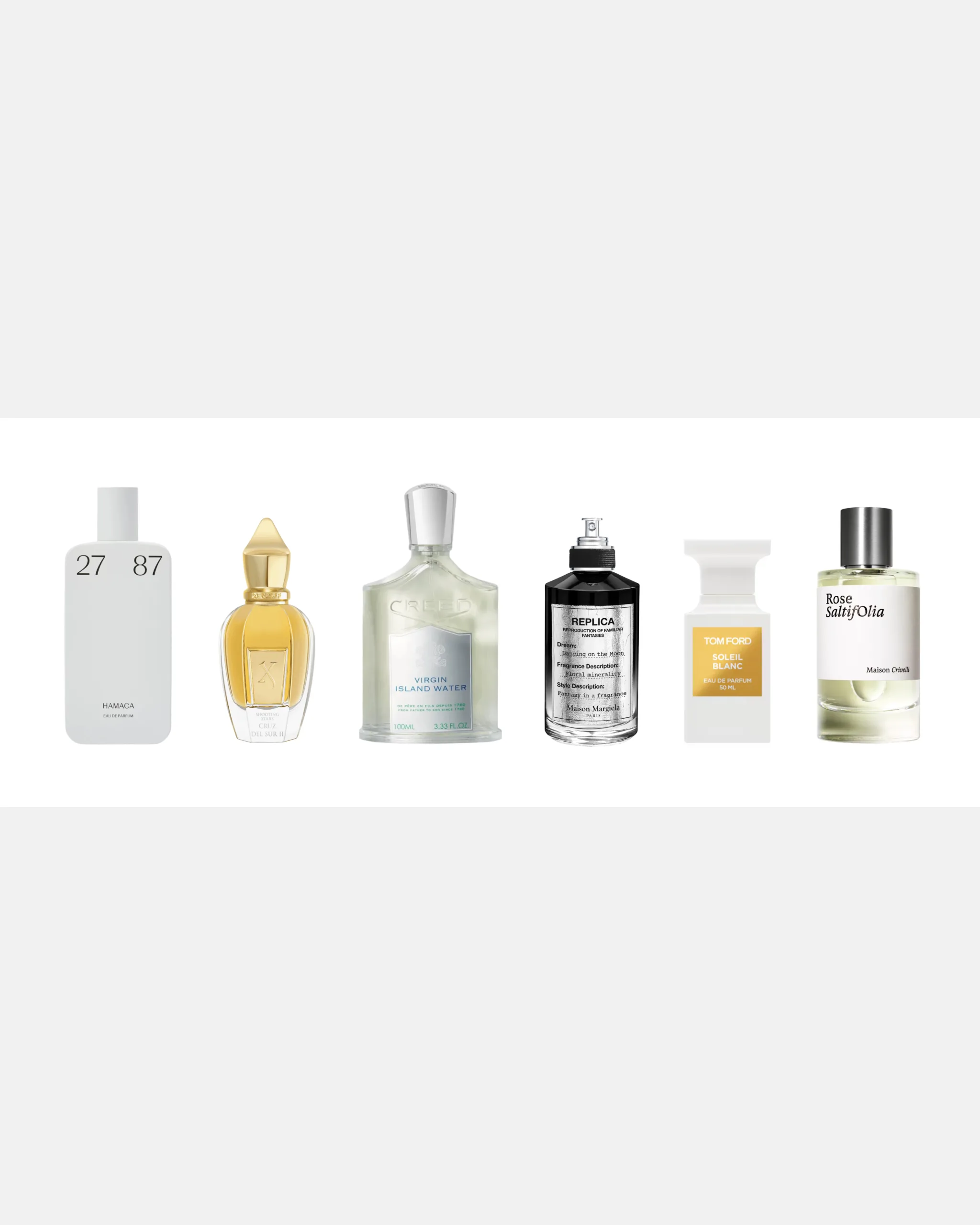 Row of perfume bottles in varying shapes and colors lined up on a white surface against a light gray background.